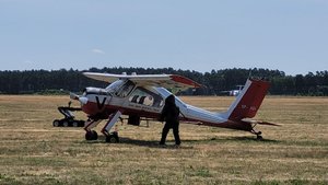 samolot, robot i osoba w kombinezonie ochronnym na terenie lotniska