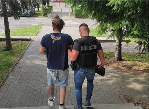 policjant prowadzi zatrzymanego po schodach