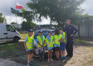 dzieci wraz z policjantem przy policyjnym radiowozie