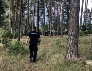 policjant idzie przez las w stronę obozowiska
