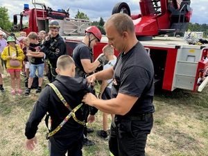 Strażak zapinający uprząż wspinaczkową dziecku