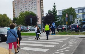 policjanci i Polfinek wraz z dziećmi na przejściu dla pieszych