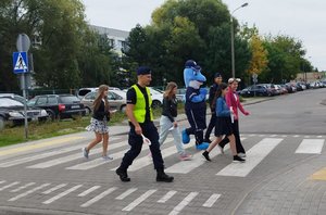 policjanci i Polfinek wraz z dziećmi na przejściu dla pieszych