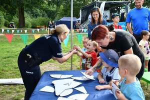 policjantka i dzieci podczas rozwiązywania rebusów przy stole