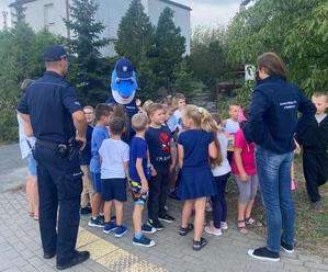 Policjanci i dzieci podczas zajęć na terenie przyszkolnym.