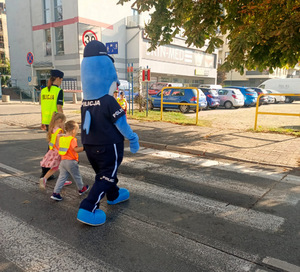 Policjantka i polfinek przechodzą z dziećmi przez przejście dla pieszych
