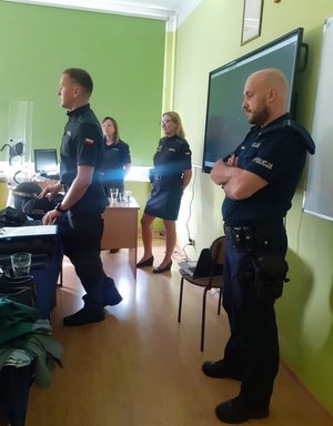 Policjanci i strażnicy więzienni podczas zajęć z uczniami w klasie szkolnej.