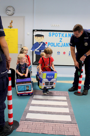 Policjant tłumaczący dzieciom zasady ruchu drogowego