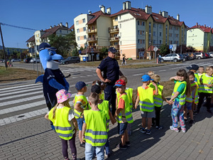 Dzieci uczestniczące w zajęciach z policjantami i Polfinkiem przy przejściu dla pieszych