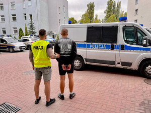 policjant prowadzi zatrzymanego do radiowozu