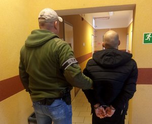 Policjant prowadzi zatrzymanego.