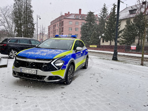 Oznakowany radiowóz stojący na parkingu przy drodze