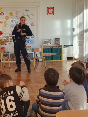 Policjantka i dzieci podczas zajęć w sali przedszkola.