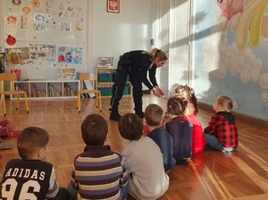 Policjantka i dzieci podczas zajęć w sali przedszkola.