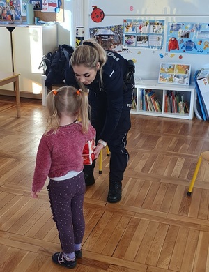 Policjantka i dzieci podczas zajęć w sali przedszkola.