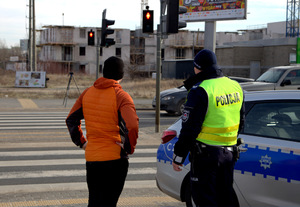 Policjanci w trakcie legitymowania osoby, która przeszła na przejściu dla pieszych na czerwonym świetle
