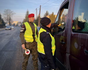 Policjantka wspólnie z funkcjonariuszem Żandarmerii Wojskowej podczas działań na drodze