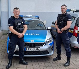 Policjanci stojący przy radiowozie.