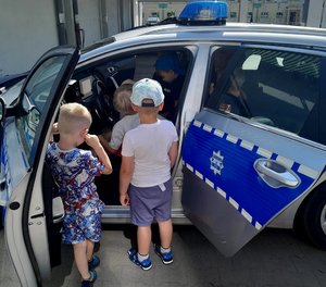 Dzieci i policjanci podczas zwiedzania komisariatu.