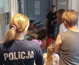 Dzieci i policjanci podczas zwiedzania komisariatu.