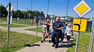 Policjant i uczniowie w miasteczku rowerowym.