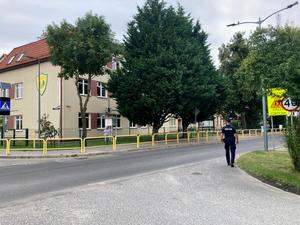 Policjant podczas kontroli infrastruktury drogowej przy szkole.