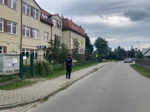 Policjant podczas kontroli infrastruktury drogowej przy szkole.