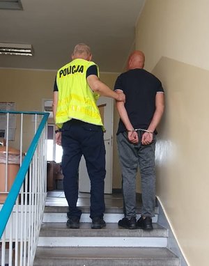 Policjant prowadzi zatrzymanego.