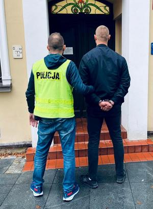 Policjant prowadzi zatrzymanego do prokuratury.