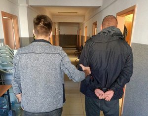 Nieumundurowany policjant prowadzi zatrzymanego.