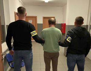 Policjanci prowadzą zatrzymanego.