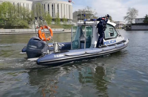 Policjanci płyną policyjną łodzią motorową.