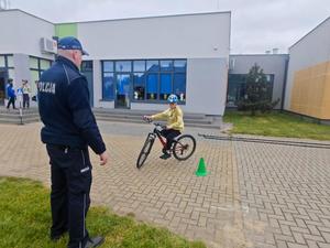 Dzielnicowy i uczniowie podczas egzaminu praktycznego na kartę rowerową.