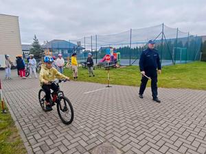 Dzielnicowy i uczniowie podczas egzaminu praktycznego na kartę rowerową.