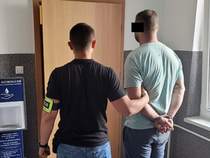 Policjant stoi wraz z zatrzymanym.