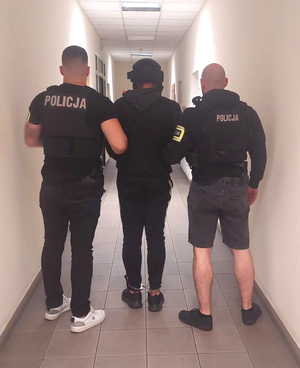 Policjanci prowadzą zatrzymanego.