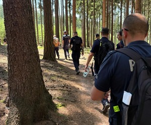 Policjanci podczas marszu w terenach zielonych.