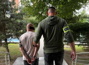 policjant prowadzi zatrzymanego