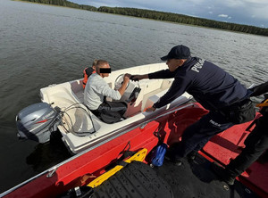 Policjant bada trzeźwość sternika łodzi motorowej.