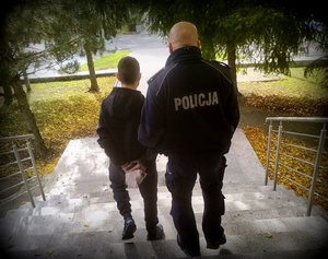 Policjant prowadzi zatrzymanego.