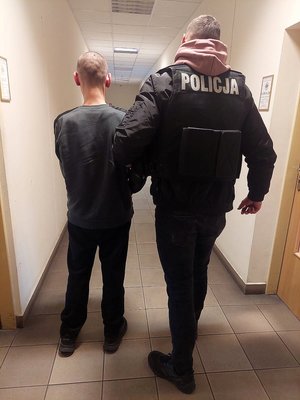 policjant prowadzi zatrzymanego