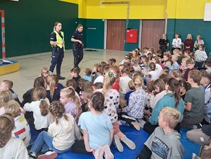 Policjantki i uczniowie podczas spotkania odbywającego się w sali gimnastycznej.