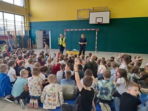 Policjantki i uczniowie podczas spotkania odbywającego się w sali gimnastycznej.