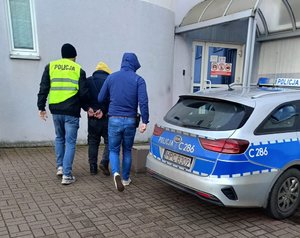 Policjanci prowadzą zatrzymanego.