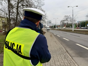 Policjant ruchu drogowego mierzącego prędkość i zatrzymujący pojazd do kontroli drogowej.