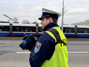 Policjant ruchu drogowego mierzącego prędkość i zatrzymujący pojazd do kontroli drogowej.