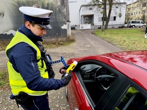 Policjant ruchu drogowego mierzącego prędkość i zatrzymujący pojazd do kontroli drogowej.