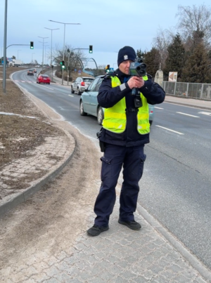 policjant mierzący prędkość ręcznym miernikiem