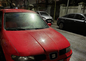 auto zaparkowane na ulicy, w tle stojące osoby i inne pojazdy oraz budynki