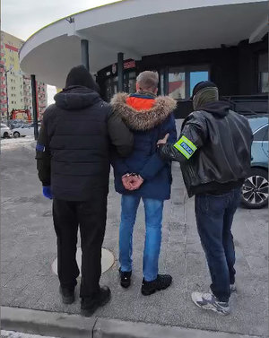 Policjanci prowadzą zatrzymanego.